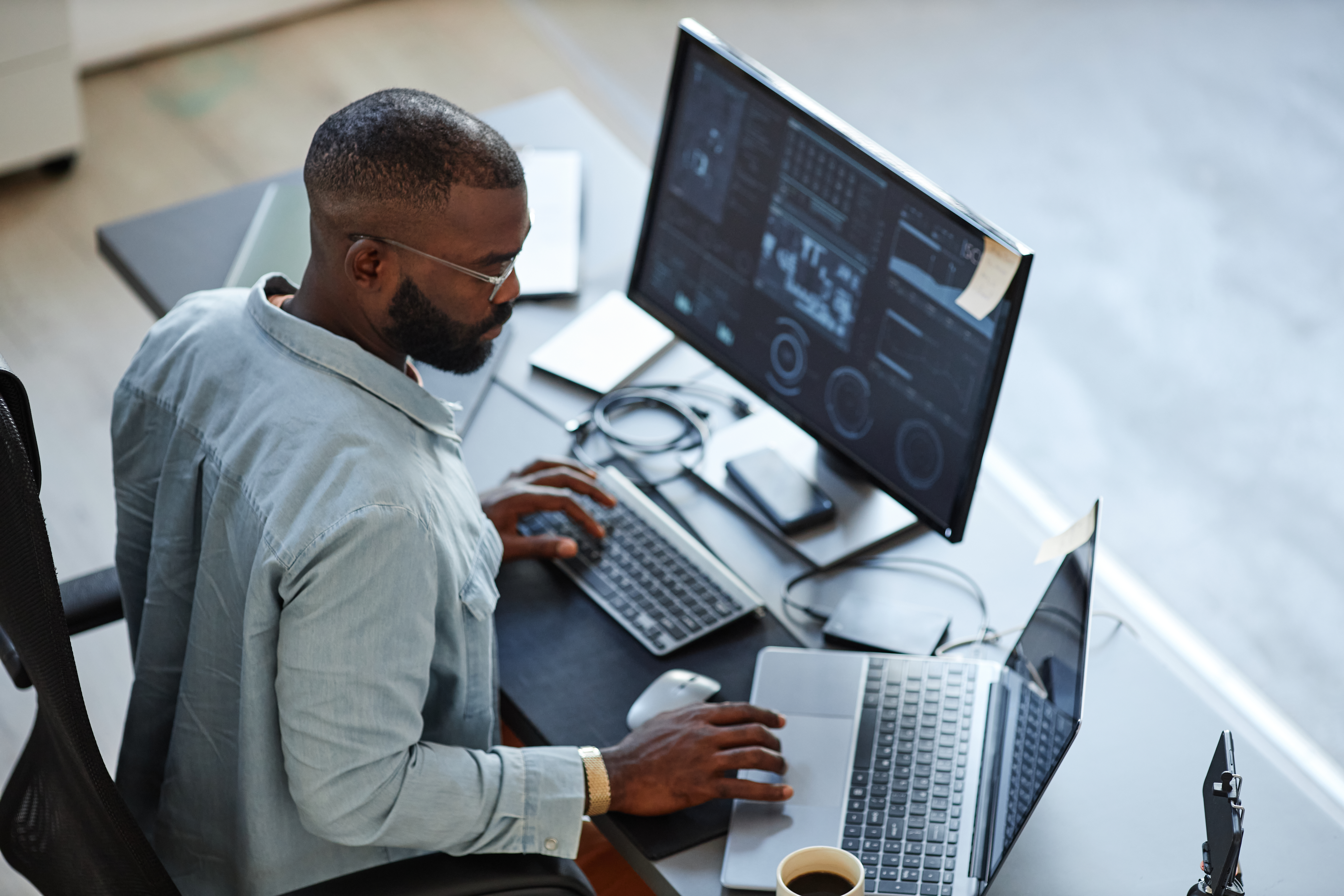 Man working on laptop and desktop computer